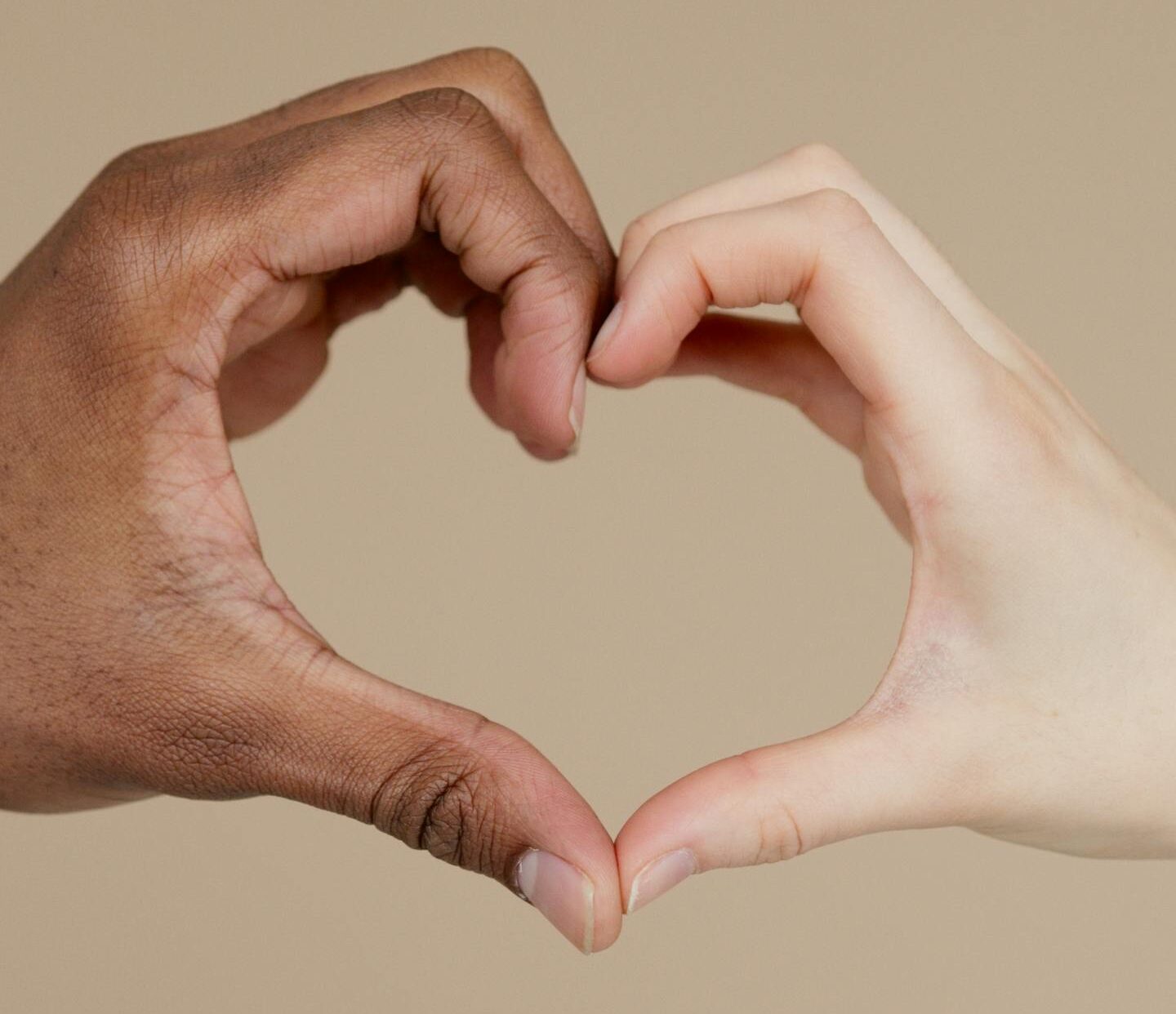 Two hands of different ethnicities form a heart shape, symbolizing unity and diversity.